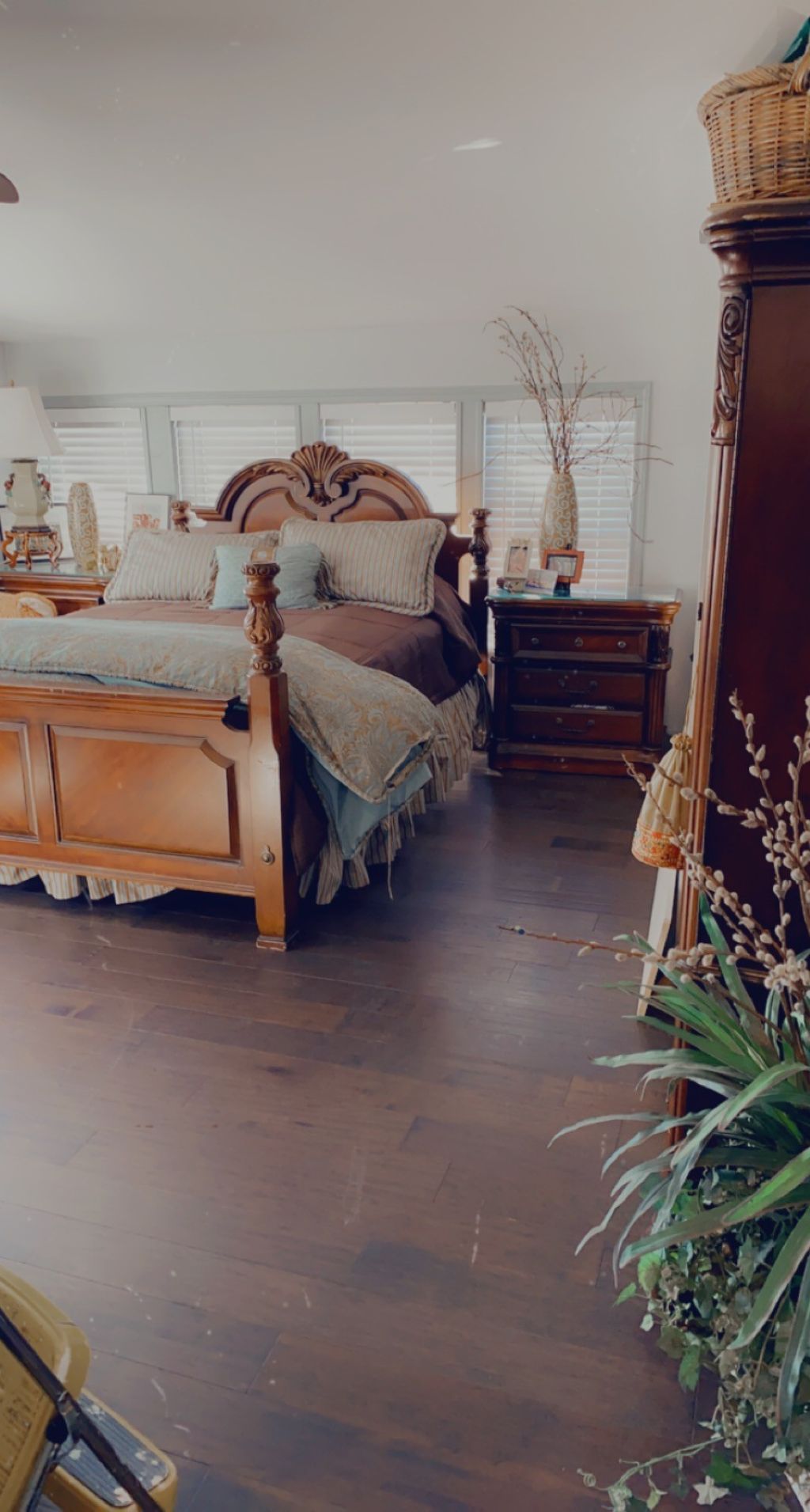 A bedroom with a wooden bed, bedside tables, a dresser, and a window with blinds.