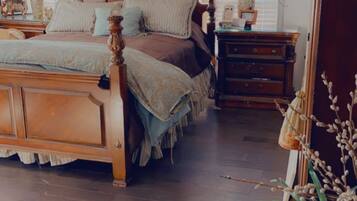 A bedroom with a wooden bed, bedside tables, a dresser, and a window with blinds.