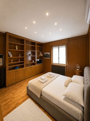 Ein Schlafzimmer mit einem großen Bett, Holzregalen, einer Heizung und einem Fenster.