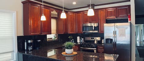 Una cocina moderna con armarios de madera oscura, electrodomésticos de acero inoxidable y una isla central con taburetes de bar.