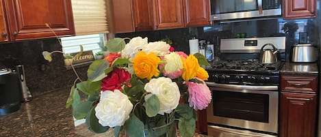 A kitchen with wooden cabinets, a microwave, a stove, and a vase of flowers on the counter.