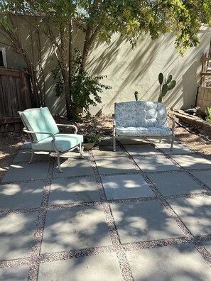 Un espace patio avec deux chaises et un cactus.