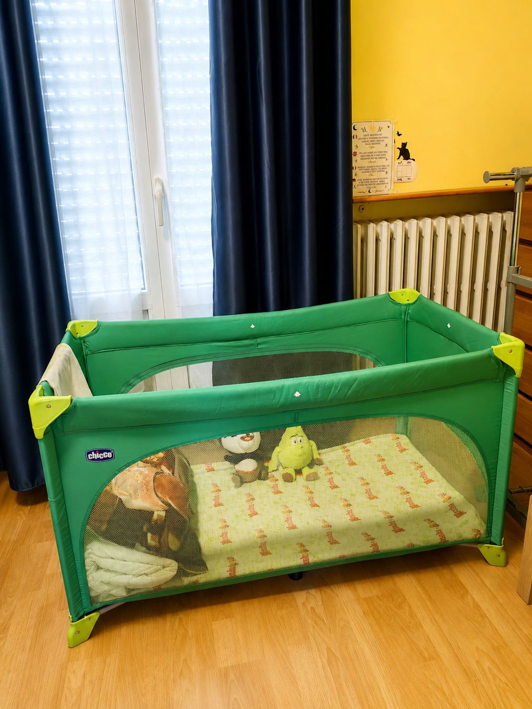 Een groene babyren met een gaaswand, een pluche speeltje en een patroonmatje aan de binnenkant.
