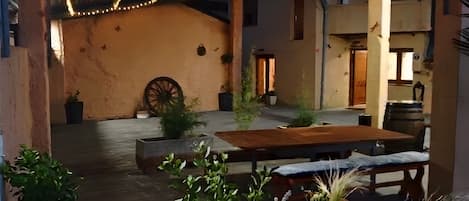 An outdoor patio area with string lights, a wooden table, and potted plants.