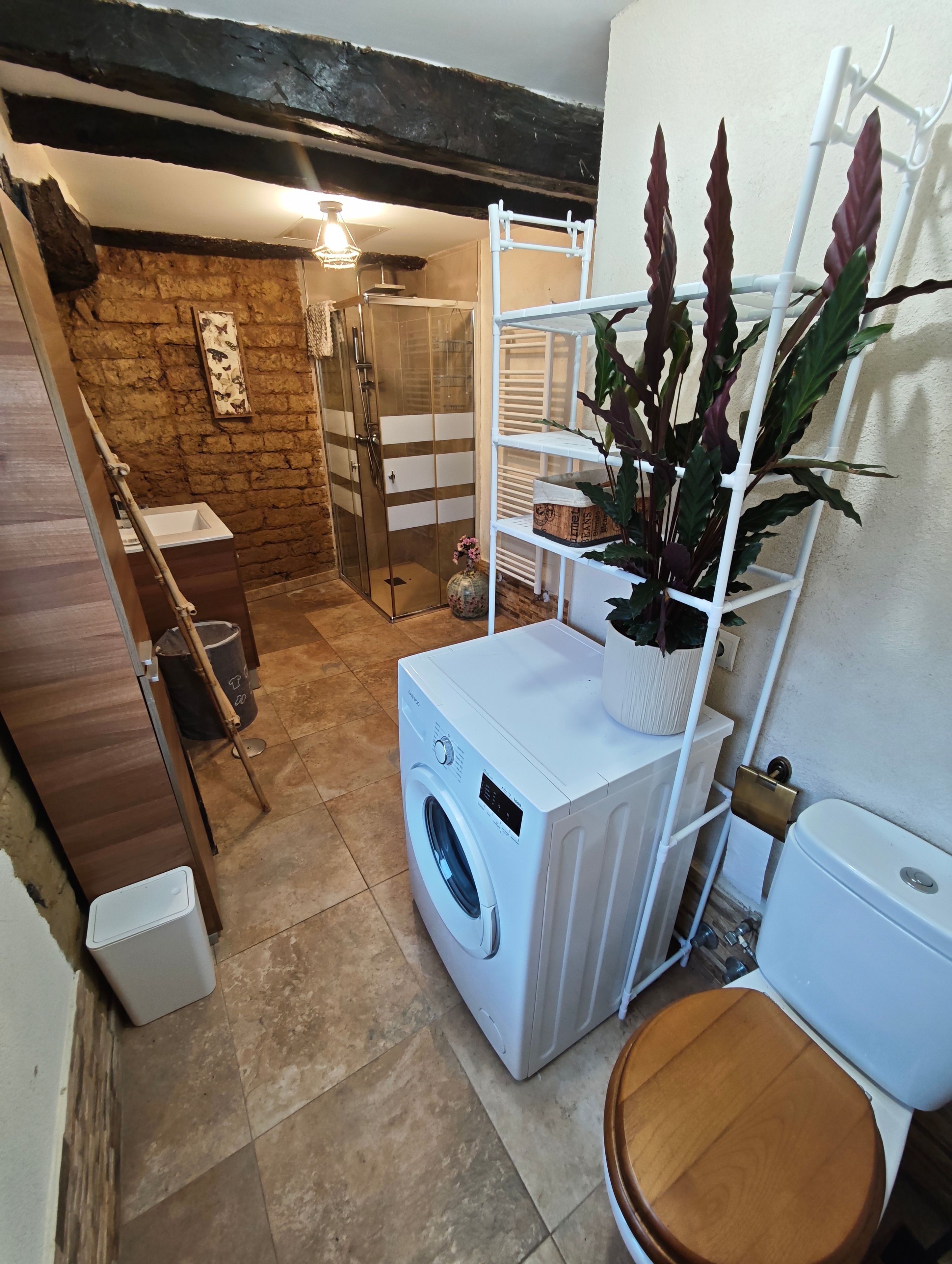 Une petite buanderie équipée d’un lave-linge, d’un étendoir et de toilettes.