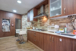 Una cocina moderna con armarios de madera, un microondas empotrado, una estufa a gas y un lavamanos de acero inoxidable.