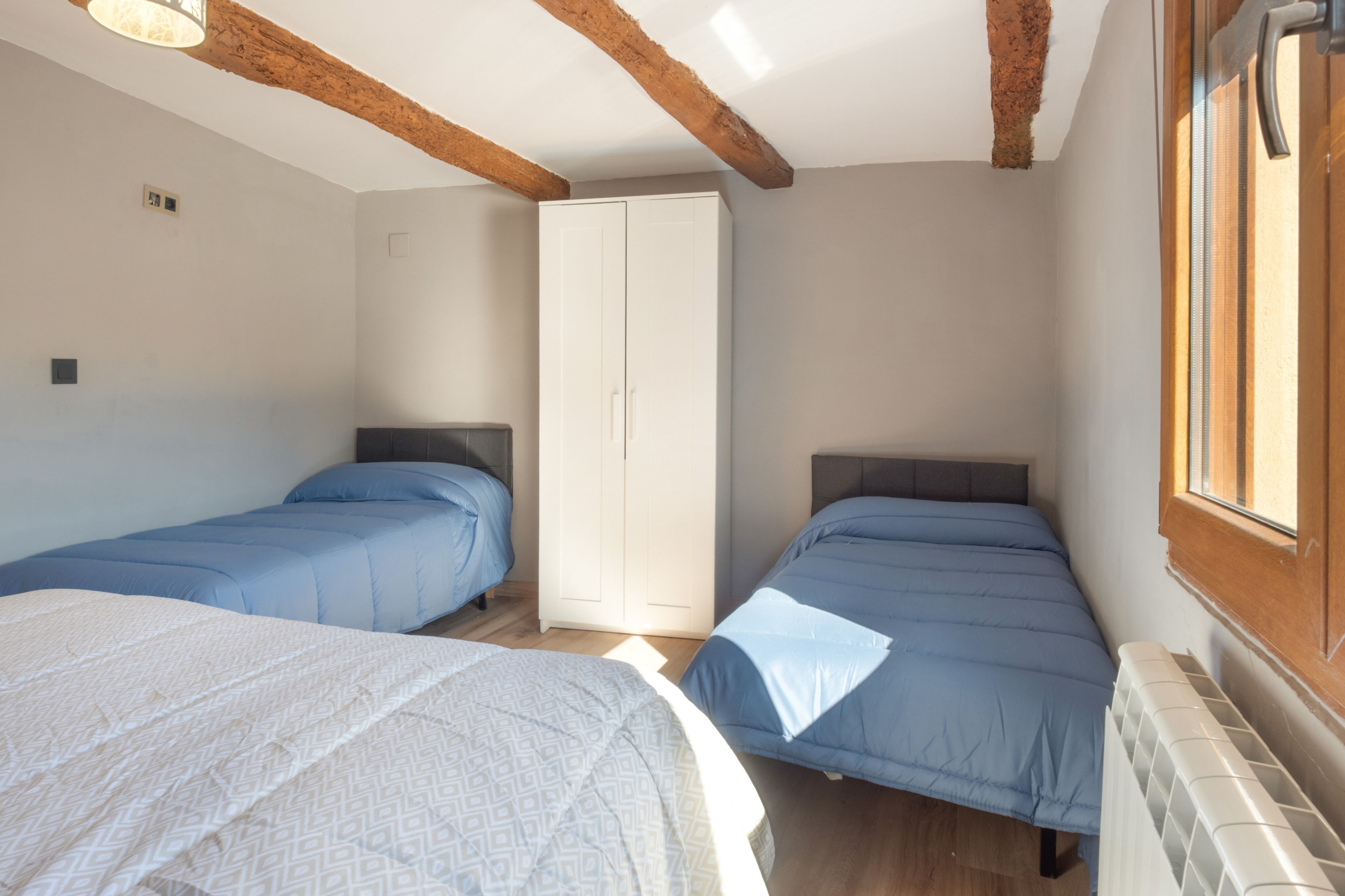 Una habitación con dos camas, un armario y una ventana.