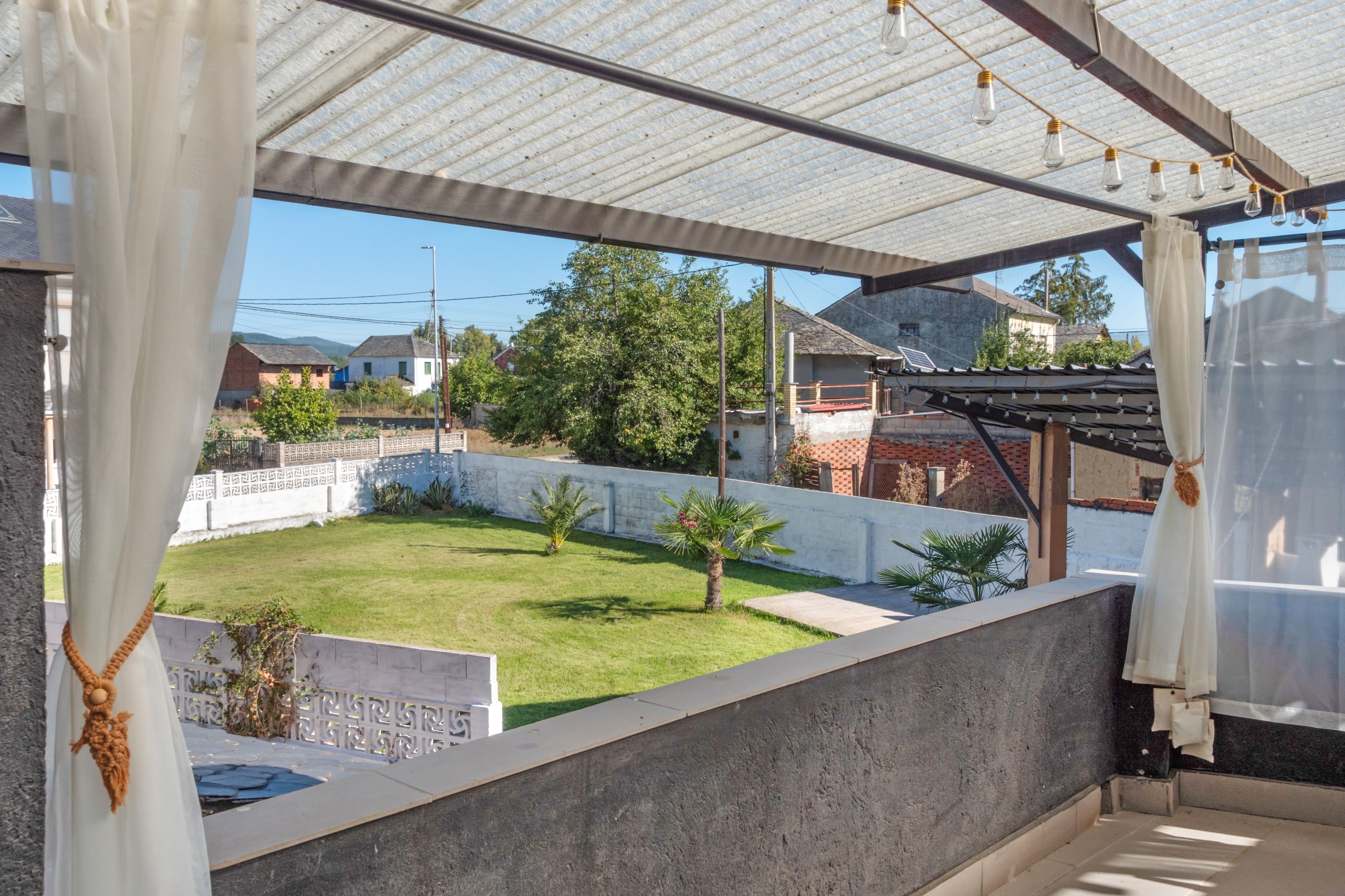 Un espacio al aire libre cubierto con vista a un patio con césped y casas al fondo.