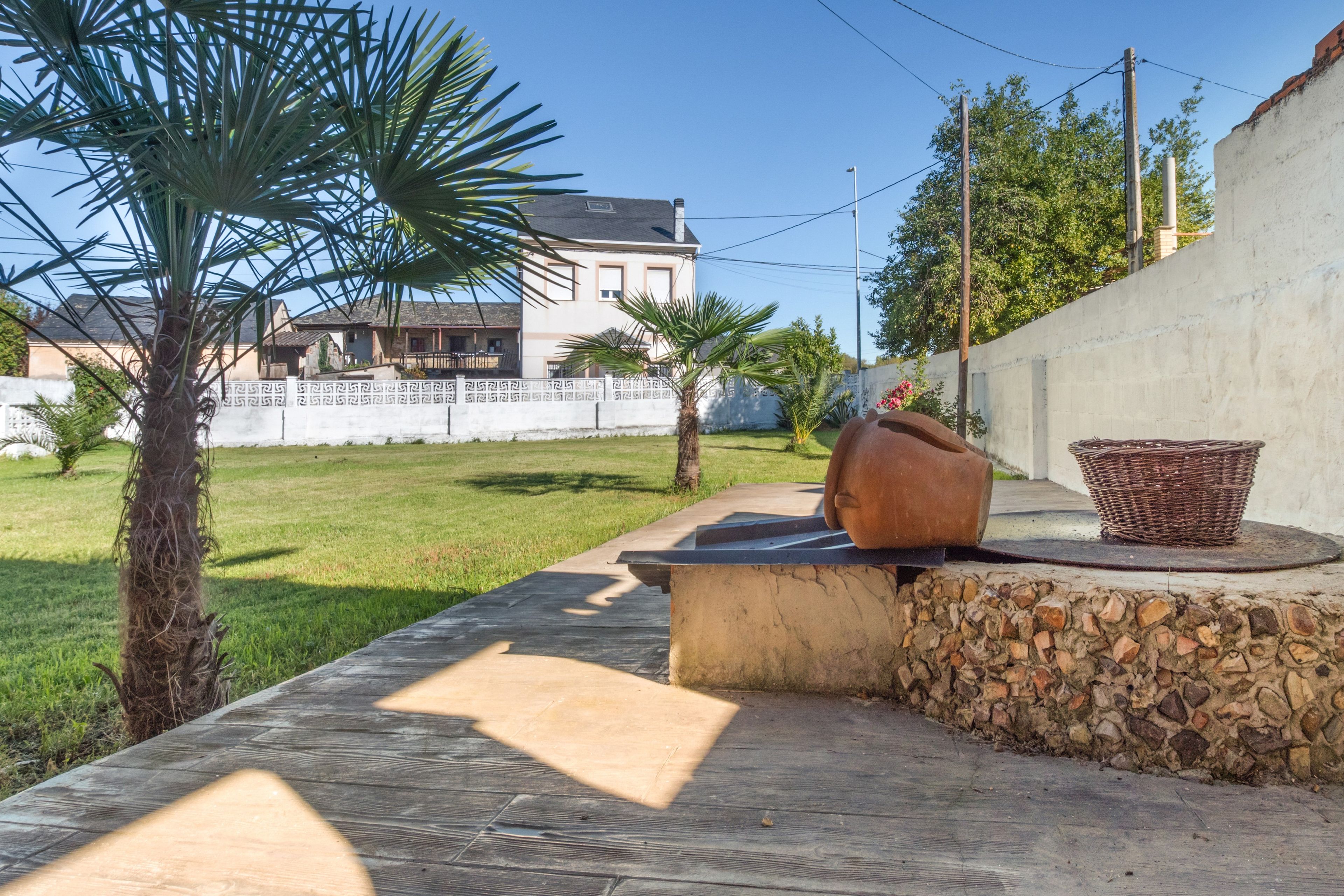 Un espace patio agrémenté d’un mur en pierre, d’un grand pot en terre cuite et d’un panier en osier.