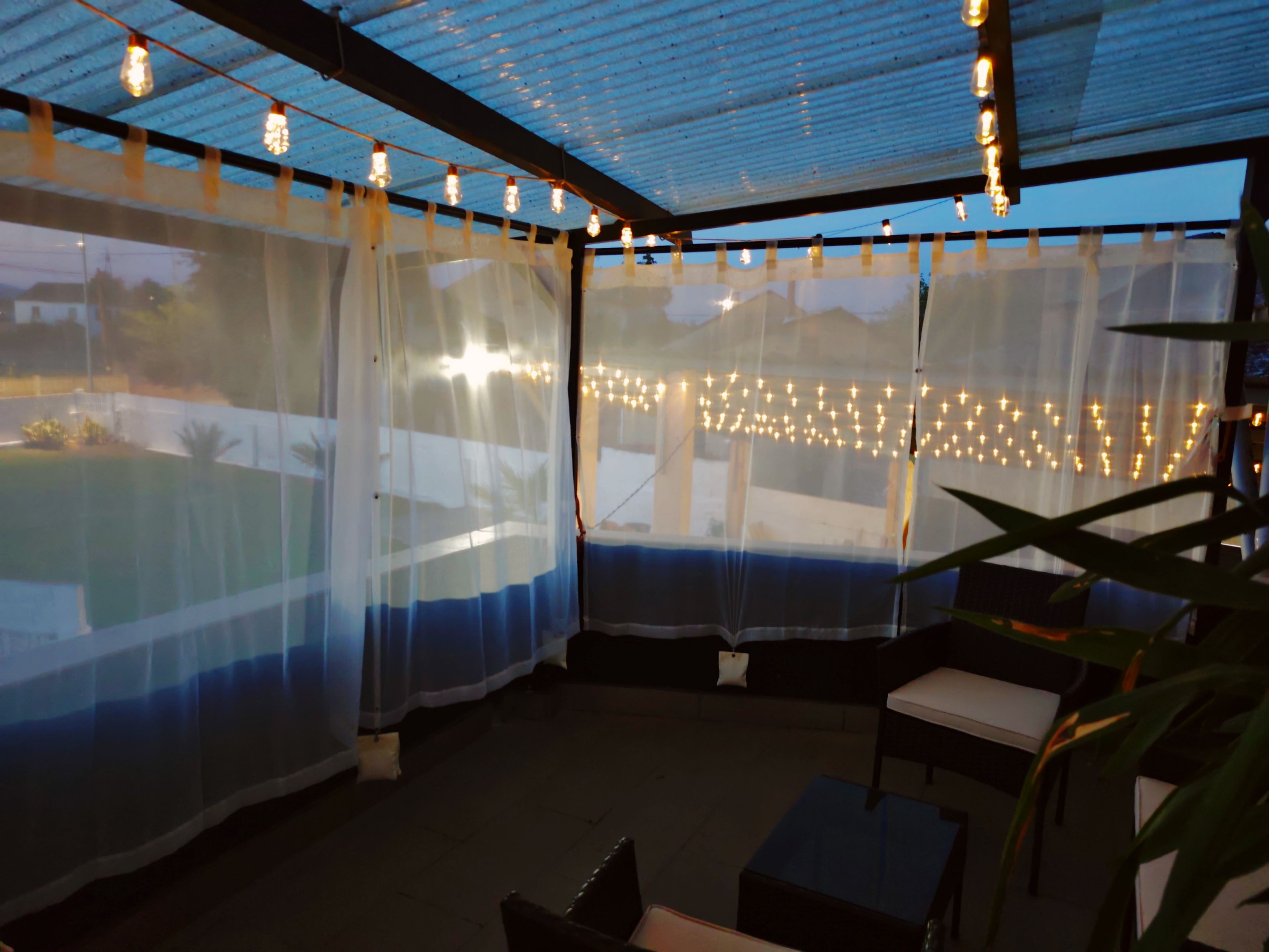 Un espace patio intérieur doté d’un plafond en verre, de guirlandes lumineuses et offrant une vue sur l’extérieur.