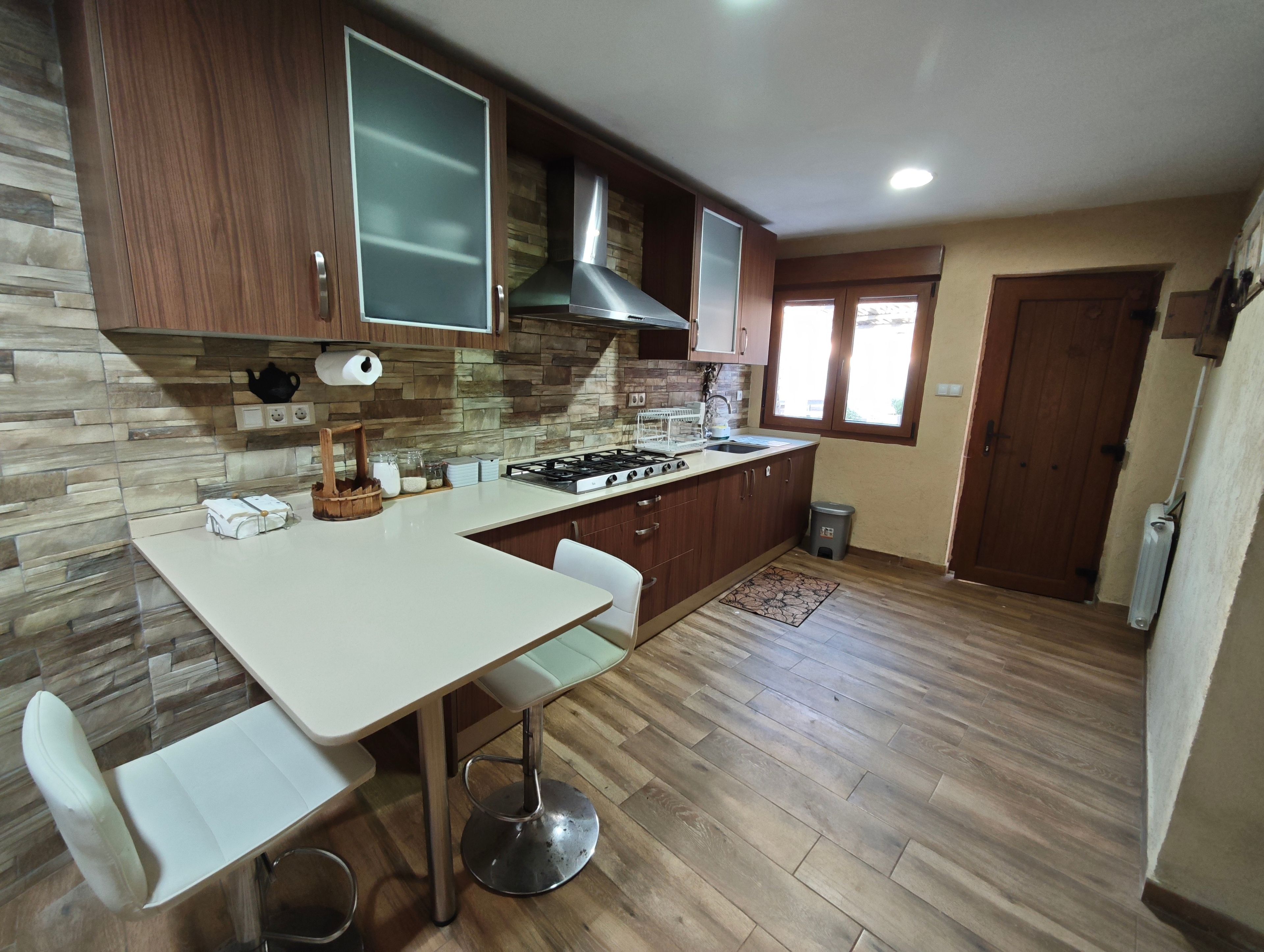 Una cocina con encimera blanca, armarios de madera, estufa a gas y ventana.