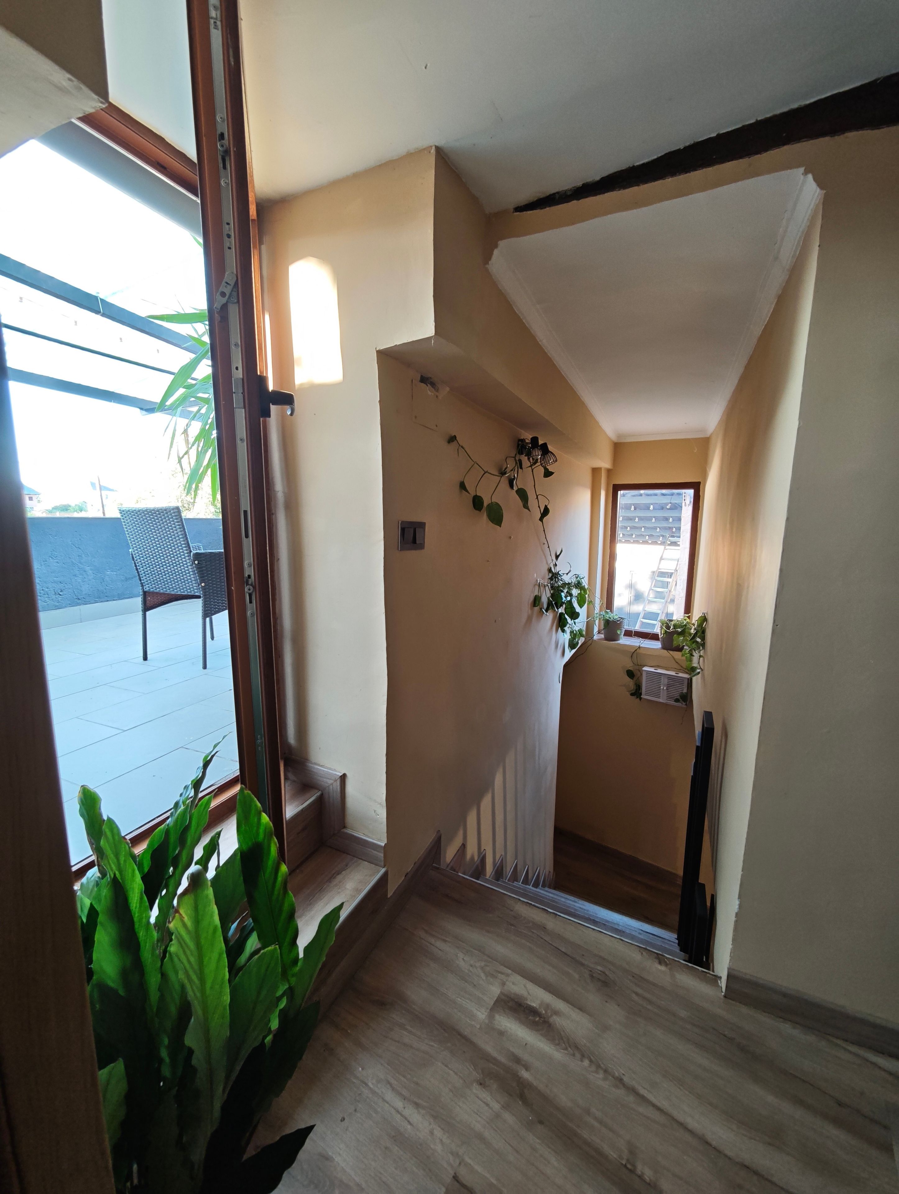 A hallway with a wooden floor, a ceiling fan, and a view of the outdoors.