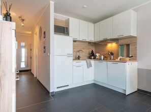 A modern kitchen with white cabinets, a microwave, and a sink. - Holiday Apartment With 2 Bedrooms (Heiligenhafen)