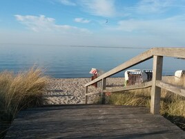A wooden boardwalk leading to a beach with a clear view of the water.