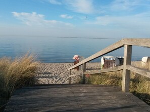 A wooden boardwalk leading to a beach with a clear view of the water. - Holiday Apartment With 2 Bedrooms (Heiligenhafen)