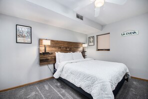 Ein Hotelzimmer mit einem hölzernen Kopfteil, einem Bett mit weißer Bettwäsche, einem Nachttisch, einer Wandlampe, einem Kalender und einem Schild mit der Aufschrift 'LA CUEVA'.