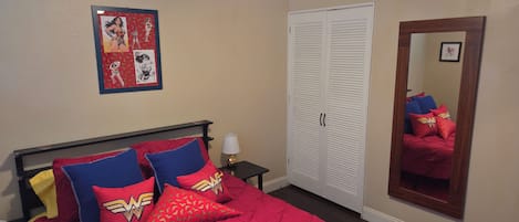 Une chambre à coucher comprenant un lit, une table de chevet, une lampe, une armoire et un ventilateur de plafond.