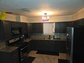 A modern kitchen with dark cabinetry, a stainless steel refrigerator, a built-in oven, and a microwave. - Hero's Hideaway, North Jackson, Sleeps 8 (Jackson)