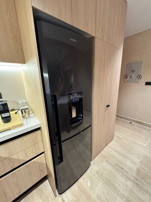 Eine moderne Küche mit einem schwarzen Kühlschrank, einer Kaffeemaschine und einem Wasserspender.