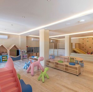 Ein Spielbereich für Kinder mit weichen Spielgeräten, einer Rutsche und einem Spielhaus.