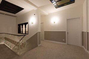 A hallway with a staircase, a door, and a wall-mounted light fixture.