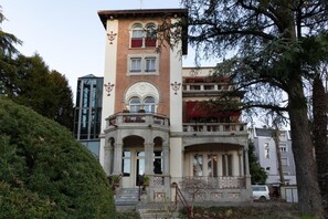 A multi-story building with a central entrance, balconies, and a staircase leading to the entrance.
