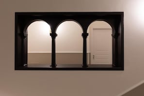 A framed architectural view of a hallway with three arches and a door.