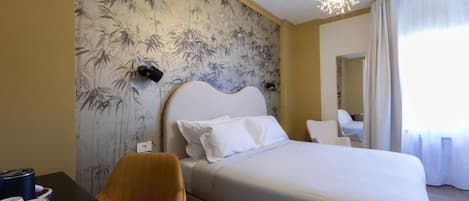Habitación de hotel con una cama, una silla, un escritorio con una bandeja de objetos y una pared con diseño de bambú.