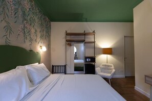Hotellihuone, jossa on sänky, tuoli, työpöytä, lamppu ja vaatekaappi.