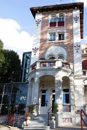 A multi-story building with a central entrance, balconies, and decorative elements.
