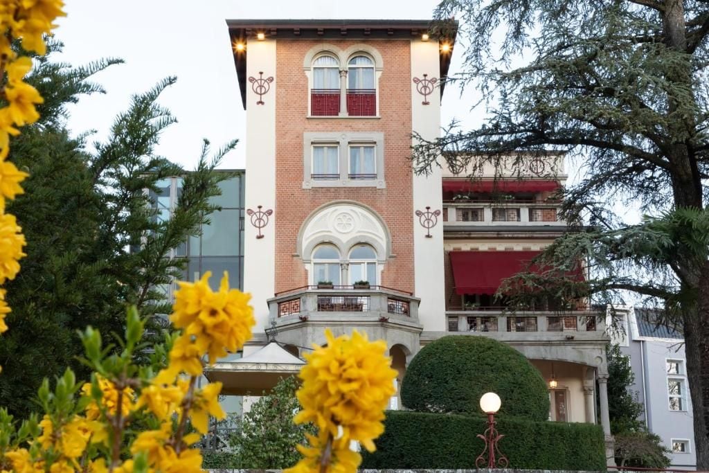 A multi-story building with a brick facade, large windows, and a balcony with railings.