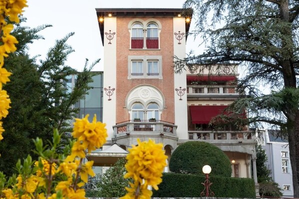 A multi-story building with a brick facade, large windows, and a balcony with railings.