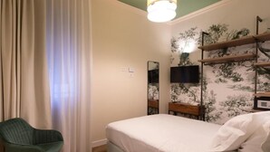 Un dormitorio con una cama, una silla, un televisor y un estante en la pared.