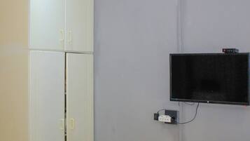 A room with a bed, a desk, a television mounted on the wall, and a wardrobe.