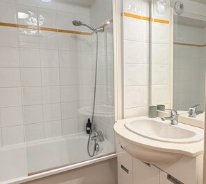 Ein Badezimmer mit einer Badewanne, einer Dusche, einem Waschbecken und einem Spiegel.