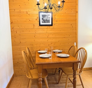Una mesa de comedor de madera con sillas, una lámpara de araña y un cuadro en la pared.