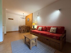 Una sala de estar acogedora con un sofá de madera, una mesita y un comedor con sillas.