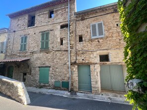 Ein Steinhaus mit mehreren Fenstern und Türen, einige mit Fensterläden, und der deutlich sichtbaren Nummer 5 an der Wand.