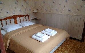 Ein Hotelzimmer mit einem Bett, zwei Kissen, einem Nachttisch mit Lampe und einer Wand mit Muster.