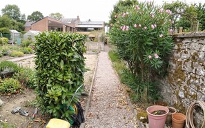 Ein Gartenweg führt zu einem Haus mit Ziegelaußenwand und Steinmauer.