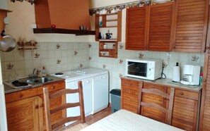 Eine kleine Küche mit Holzschränken, einer Mikrowelle, einer Kaffeemaschine und einer Waschmaschine.