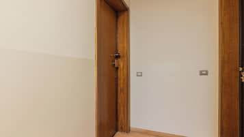 Ein Flur mit einer Holztür, einem Lichtschalter und einem kleinen Bilderrahmen an der Wand.