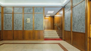 Un hall d’hôtel avec un escalier en bois et un tapis rouge menant à une porte.