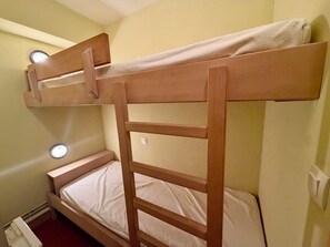 A bunk bed with a ladder and two round lights on the wall. - Studio with a balcony, right at the slopes (La Salle-les-Alpes)