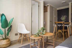 A modern living space with a dining area, a white chair, a round table, and a potted plant. - Sleek Santiago Retreat City Views for 3 (Santiago)