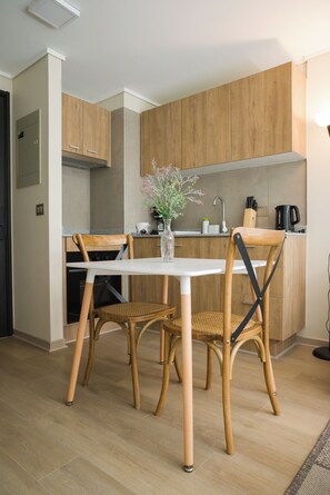 Eine moderne Küche mit Holzschränken, einer weißen Arbeitsplatte und einem Esstisch mit zwei Stühlen.