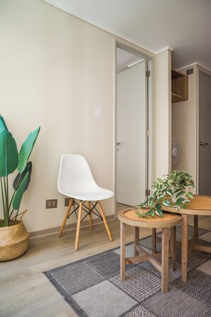 A room with a white chair, a round wooden table, a woven floor mat, and a potted plant. - Sleek Santiago Retreat City Views for 3 (Santiago)