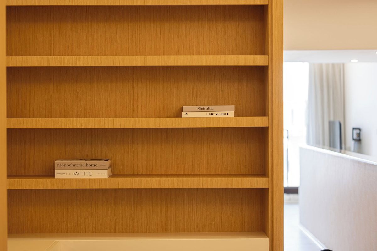 A wooden bookshelf with two books on the top shelf.