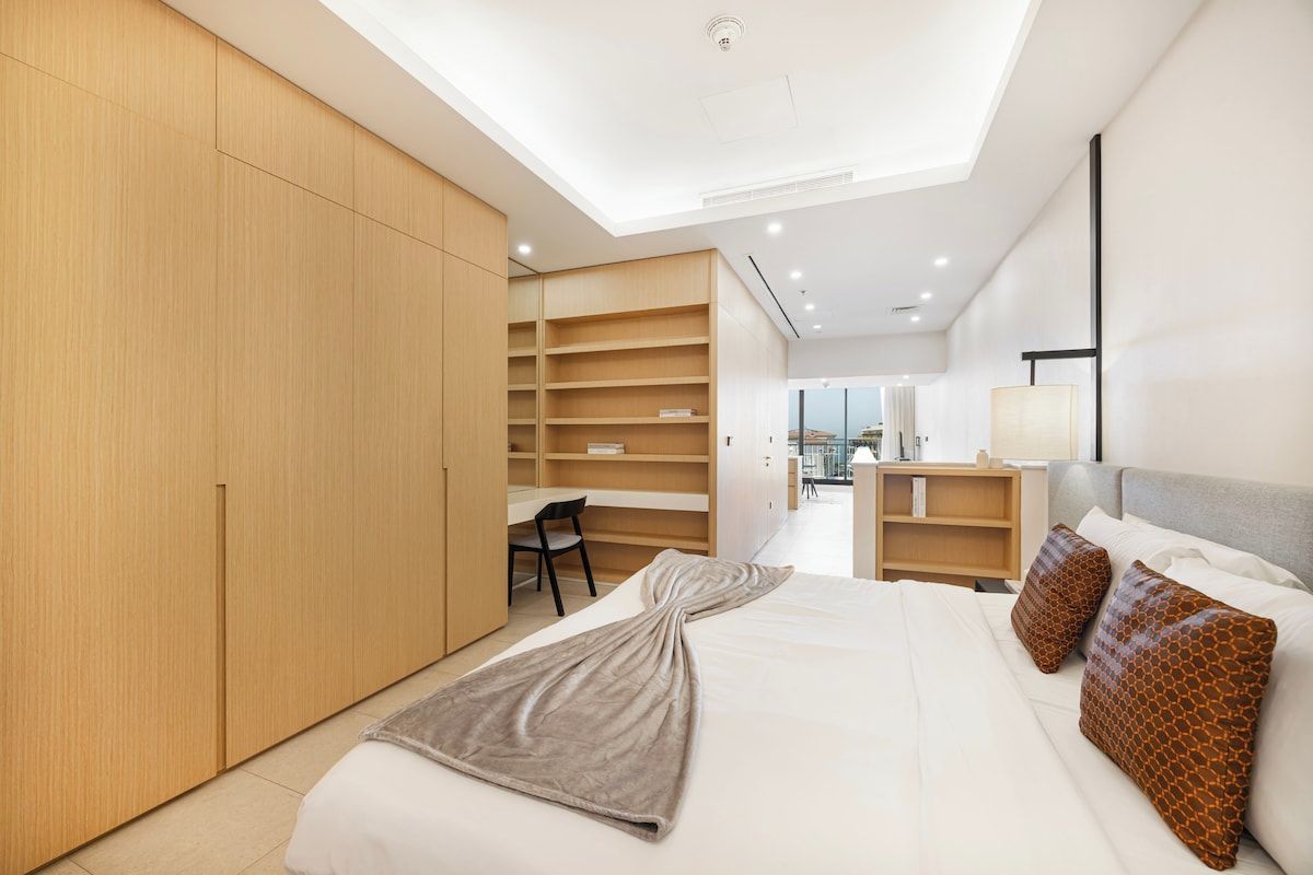 Ein modernes Schlafzimmer mit einem großen Bett, einem Einbauschrank und einem Schreibtischbereich.
