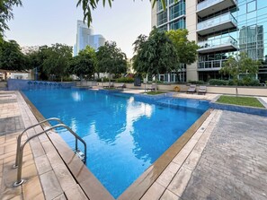 A swimming pool with a metal ladder, surrounded by a paved deck and greenery. - Full Burj Khalifa & Fountain Views/ Opp Dubai Mall (Dubai)